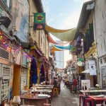 Vibrant alley with outdoor seating and decorations in Bugis, Singapore, showcasing street life.
